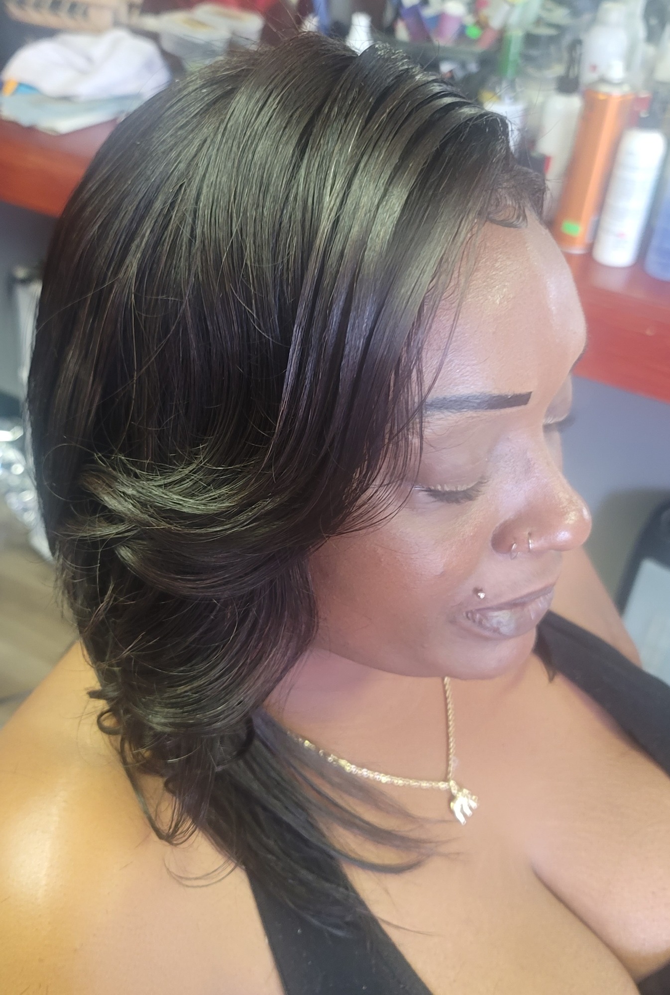 Close-up of a woman with smooth, dark hair styled in soft waves, wearing a necklace.