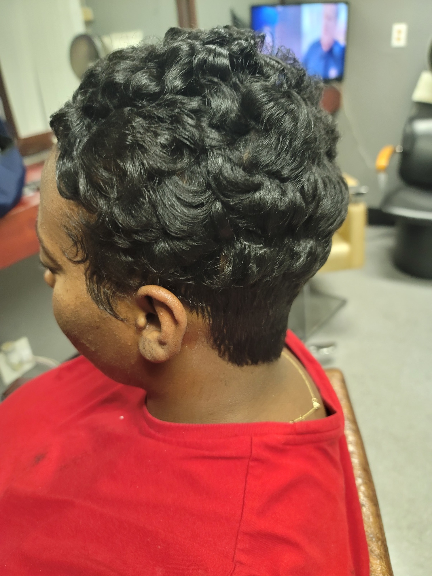 Short cropped hair with textured curls, viewed from the side. Person wearing a red shirt.