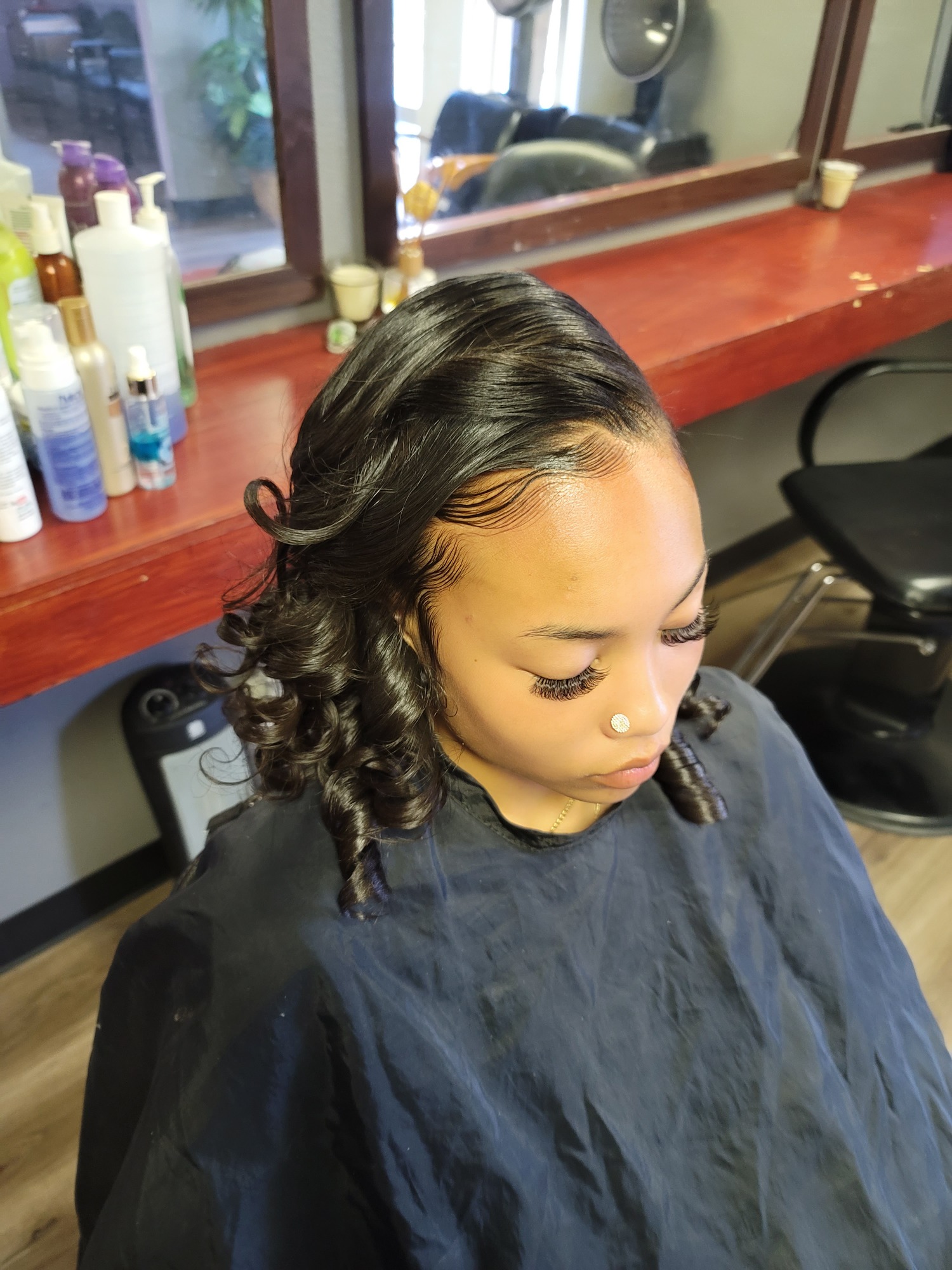 Woman with styled, curled hair, sitting in a salon chair.