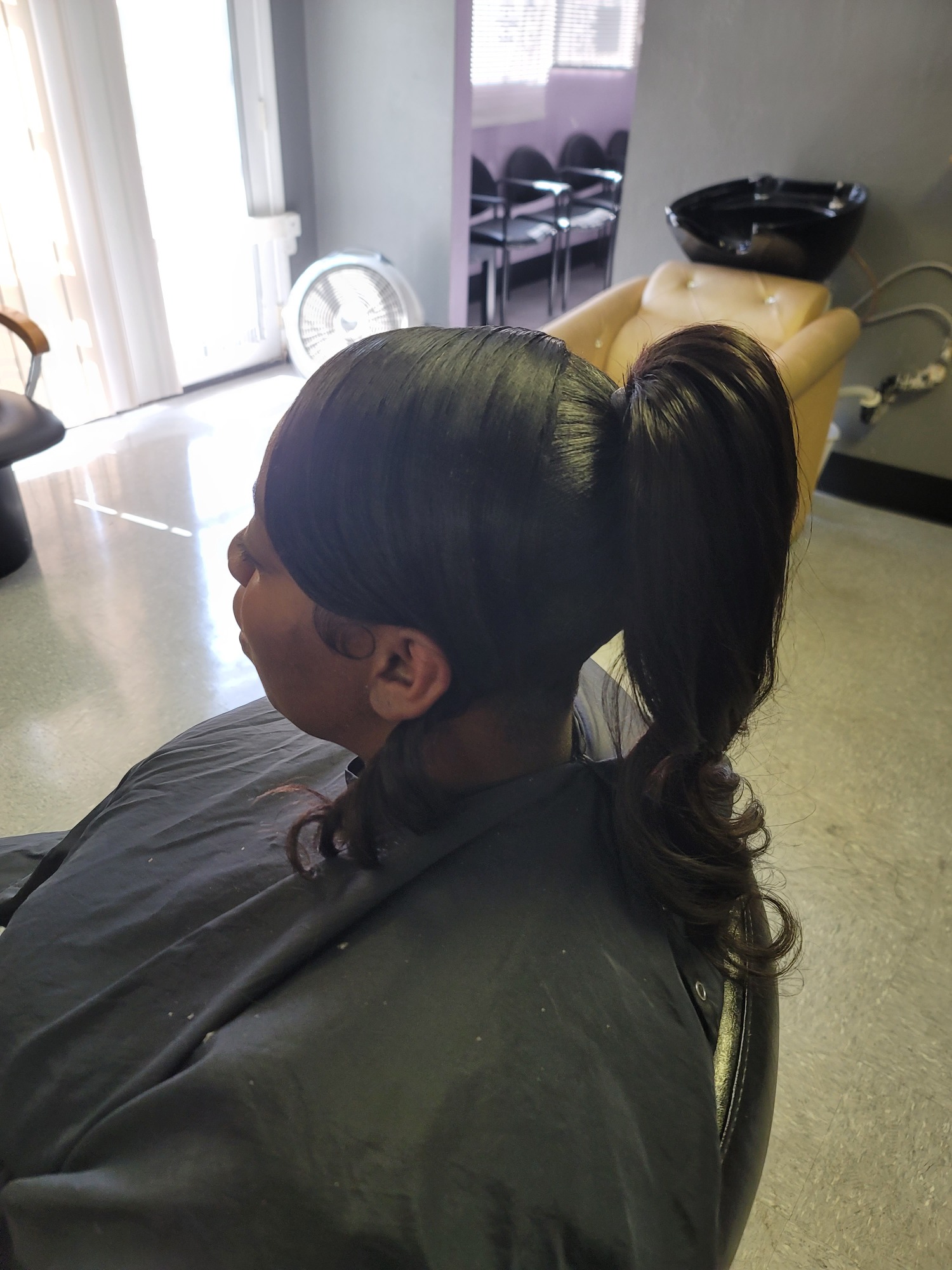 Profile view of a woman with straight, sleek hair styled in a high ponytail.